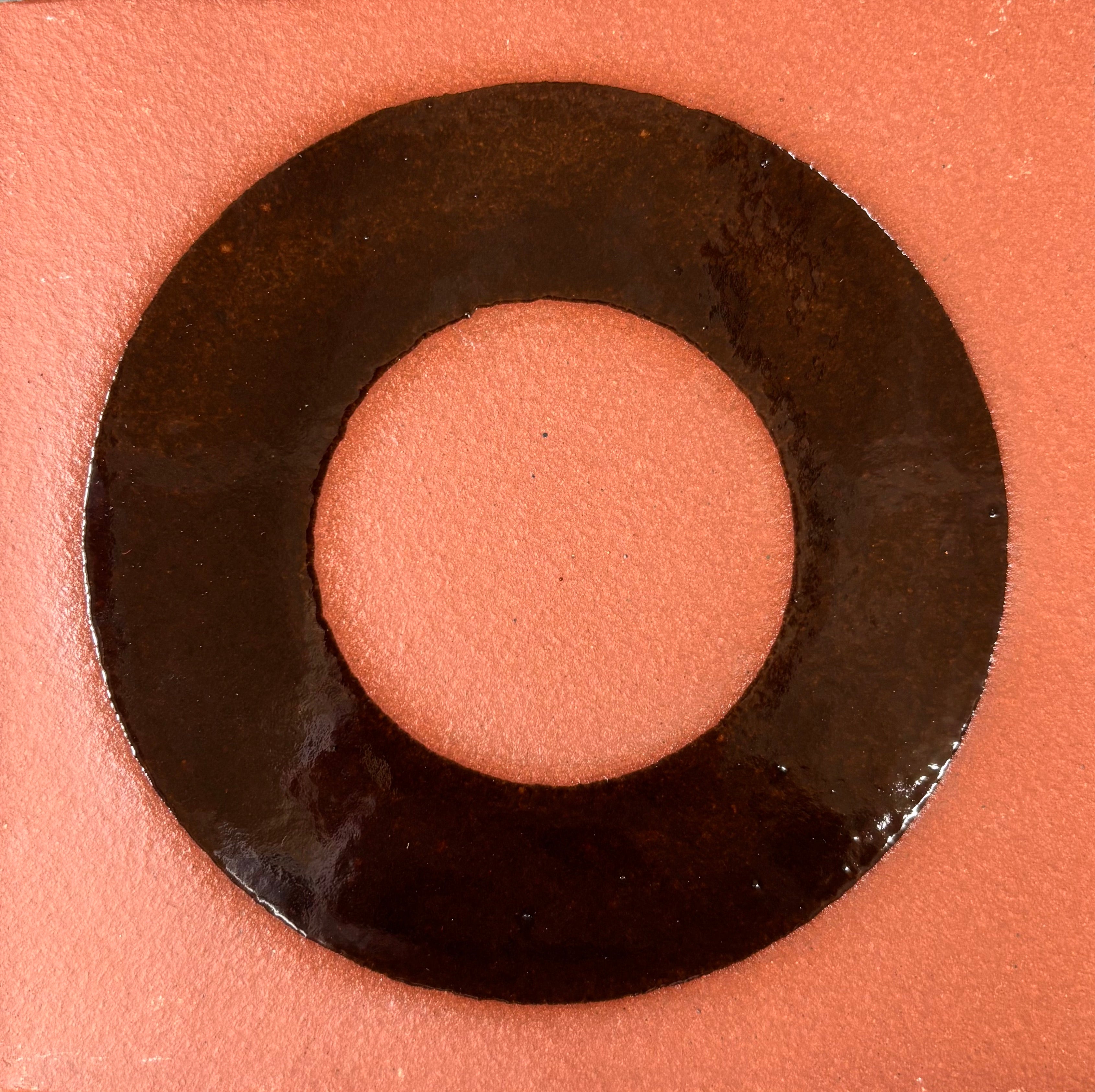 Makeup product with a black ring and pink center on a matching background