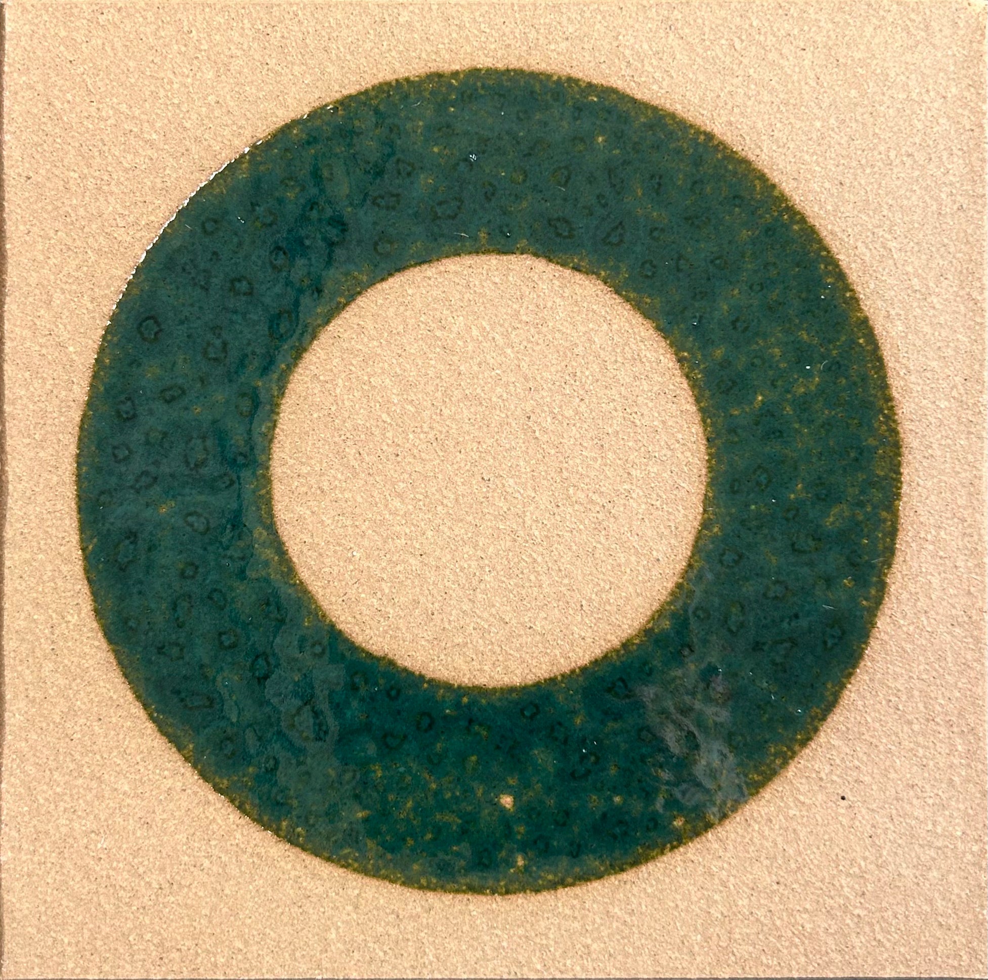 Circular green rubber gasket on a beige background